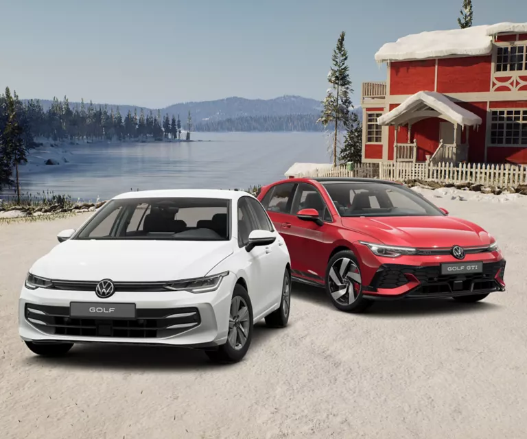 Zwei VW-Modelle stehen vor einem verschneiten Haus, im Hintergrund ein See