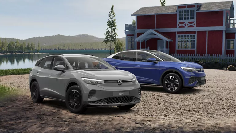 Grauer ID.4 und blauer ID.5 stehen vor einem See mit einem roten Landhaus im Hintergrund, bei bewölktem Wetter