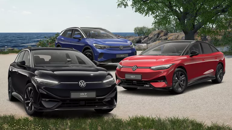 Drei VW Elektroautos stehen auf einem Kiesweg: ein schwarzer ID.7, ein blauer ID.4 und ein roter ID.7 Tourer. Im Hintergrund ist ein See und Bäume sichtbar.