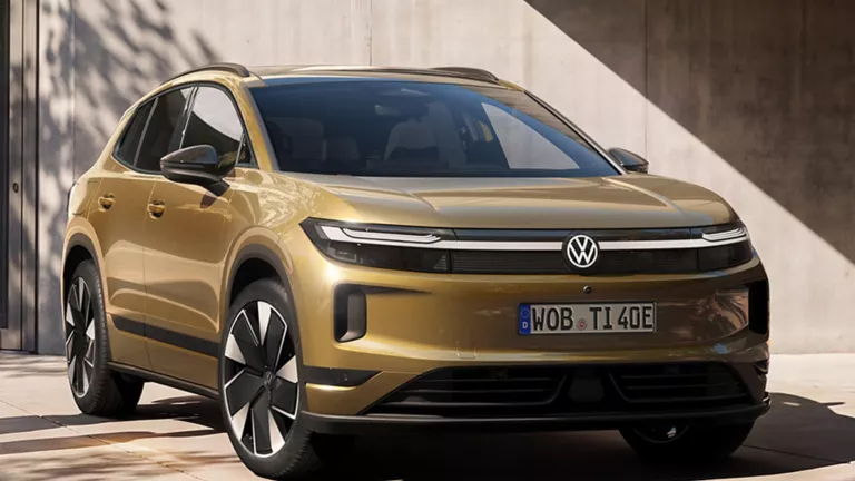 Ein oliv-bronzefarbener VW ID. Tiguan, der vor einem modernen Gebäude parkt.