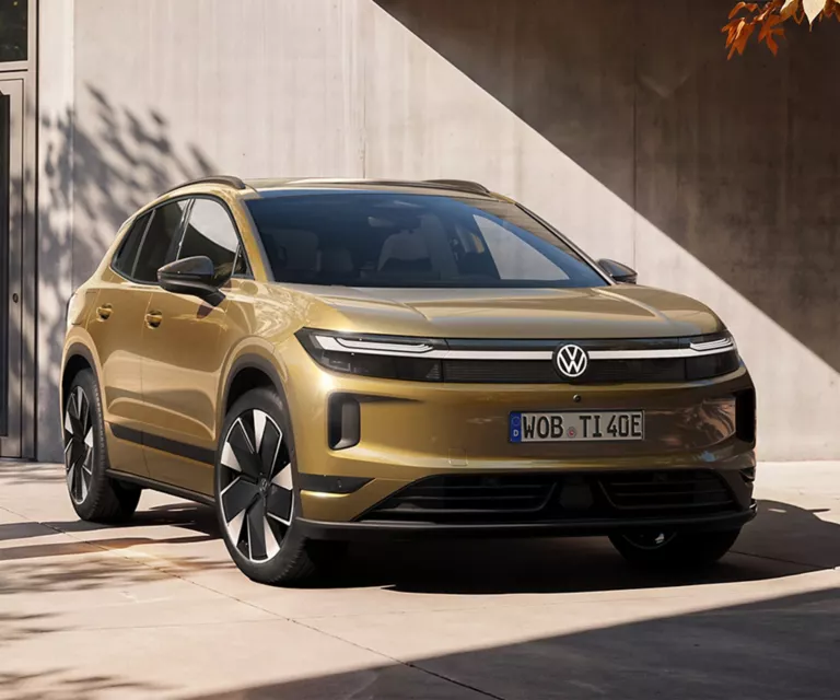 Ein oliv-bronzefarbener VW ID. Tiguan, der vor einem modernen Gebäude parkt.