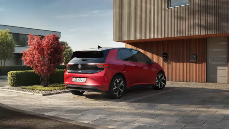  Roter Volkswagen ID.3 steht vor einem modernen Haus mit Holzfassade, aufgenommen von hinten rechts