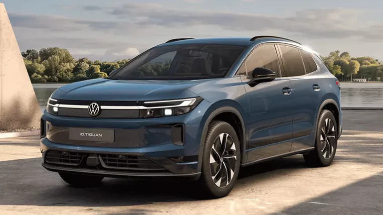 Ein oliv-bronzefarbener VW ID. Tiguan, der vor einem modernen Gebäude parkt.