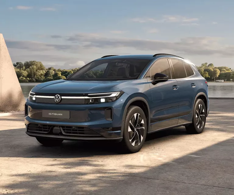 Ein oliv-bronzefarbener VW ID. Tiguan, der vor einem modernen Gebäude parkt.