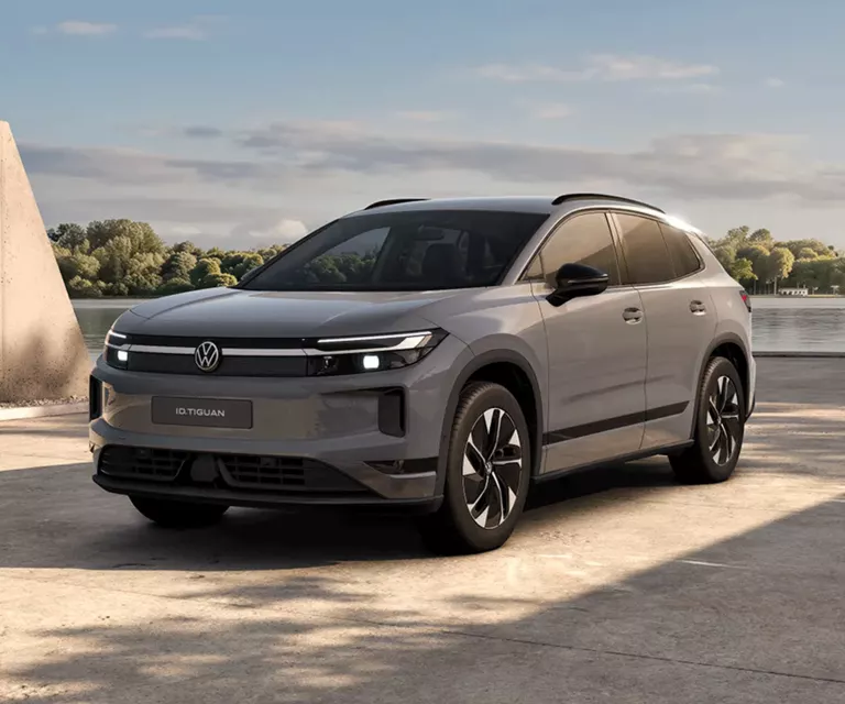 Ein grauen VW ID. Tiguan, der vor einem modernen Gebäude parkt.