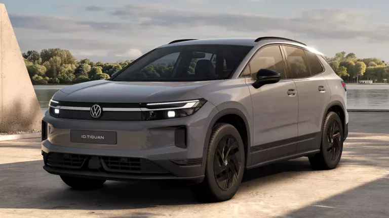 Ein oliv-bronzefarbener VW ID. Tiguan, der vor einem modernen Gebäude parkt.