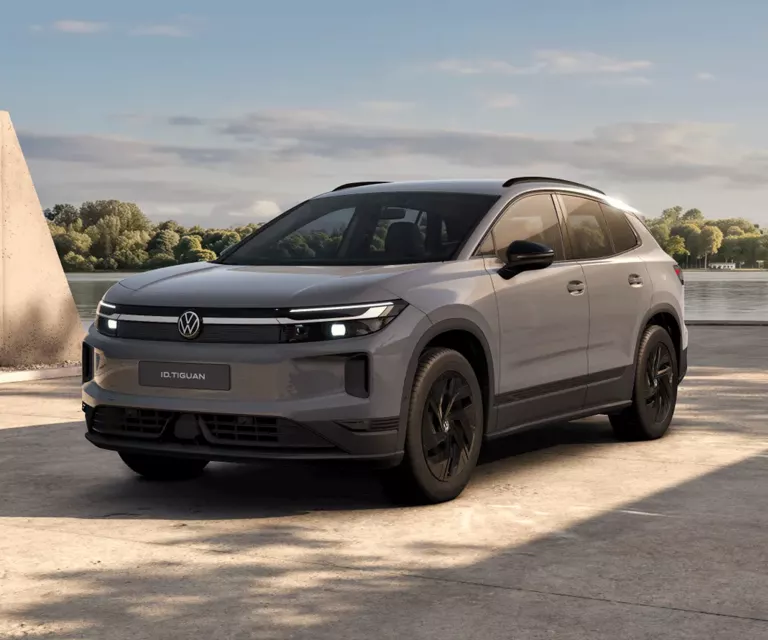 Ein oliv-bronzefarbener VW ID. Tiguan, der vor einem modernen Gebäude parkt.