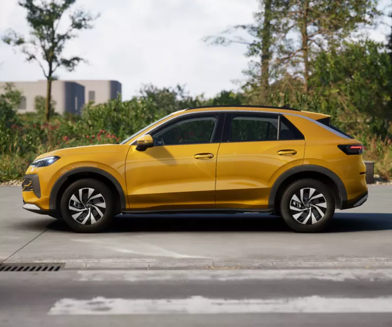 Gelber VW T-Roc SUV, Frontansicht, geparkt auf Asphalt, umgeben von Bäumen und Sträuchern.