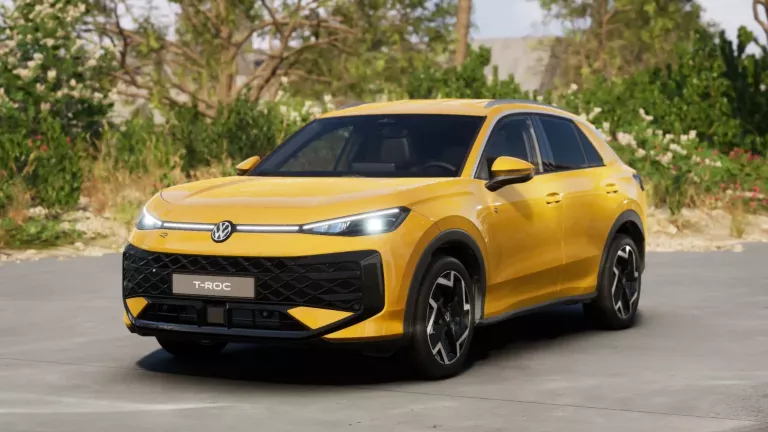 Gelber VW T-Roc SUV, Frontansicht, geparkt auf Asphalt, umgeben von Bäumen und Sträuchern.