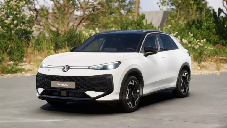 Weißer VW T-Roc SUV, Frontansicht, geparkt auf Asphalt, umgeben von Bäumen und Sträuchern.