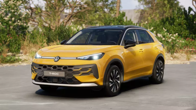 Gelber VW T-Roc SUV, Frontansicht, geparkt auf Asphalt, umgeben von Bäumen und Sträuchern.