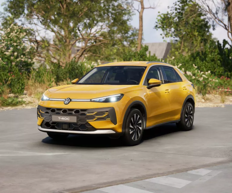 Gelber VW T-Roc SUV, Frontansicht, geparkt auf Asphalt, umgeben von Bäumen und Sträuchern.