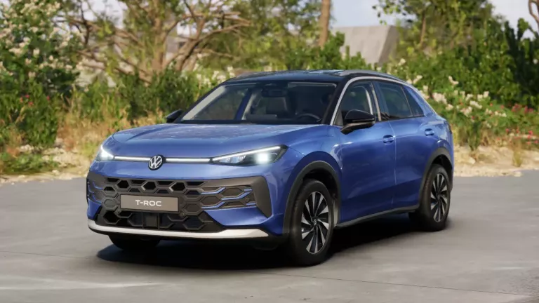 Blauer VW T-Roc SUV, Frontansicht, geparkt auf Asphalt, umgeben von Bäumen und Sträuchern.