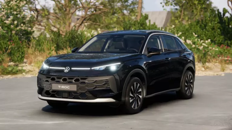 Gelber VW T-Roc SUV, Frontansicht, geparkt auf Asphalt, umgeben von Bäumen und Sträuchern.