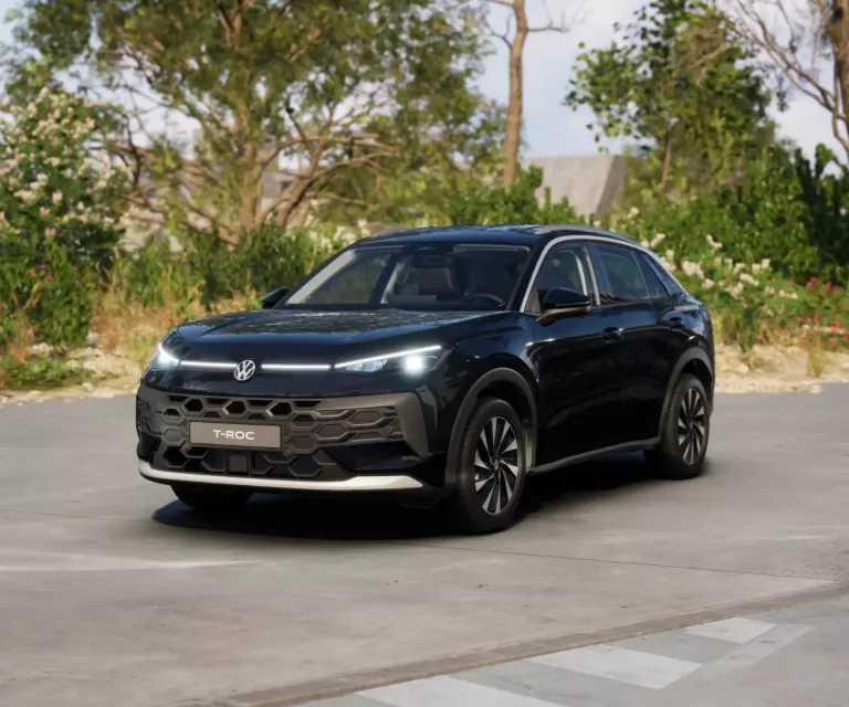 Schwarzer VW T-Roc SUV, Frontansicht, geparkt auf Asphalt, umgeben von Bäumen und Sträuchern.