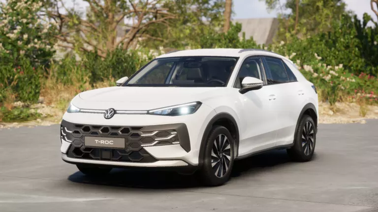 Gelber VW T-Roc SUV, Frontansicht, geparkt auf Asphalt, umgeben von Bäumen und Sträuchern.