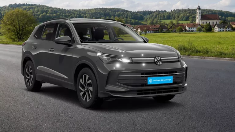 Ein VW Tiguan steht auf einer Straße. Im Hintergrund sieht man die Berge und ein kleines Dorf.