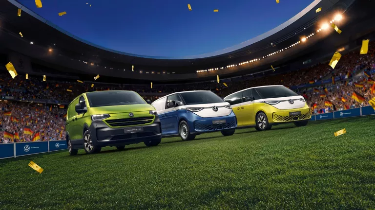 VW Transporter, VW ID. Buzz Cargo und VW ID. Buzz stehen in einem Fußballstadion umgeben von Konfettiregen.