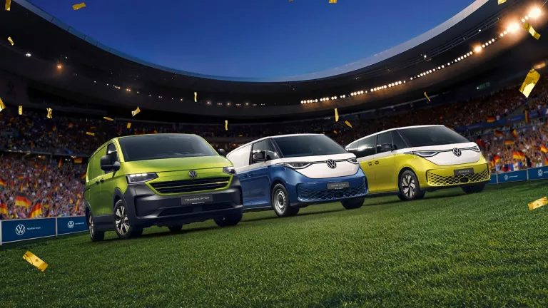 VW Transporter Kastenwagen, VW ID. Buzz Cargo und VW ID. Buzz stehen im Konfettiregen in einem Fußballstadion.