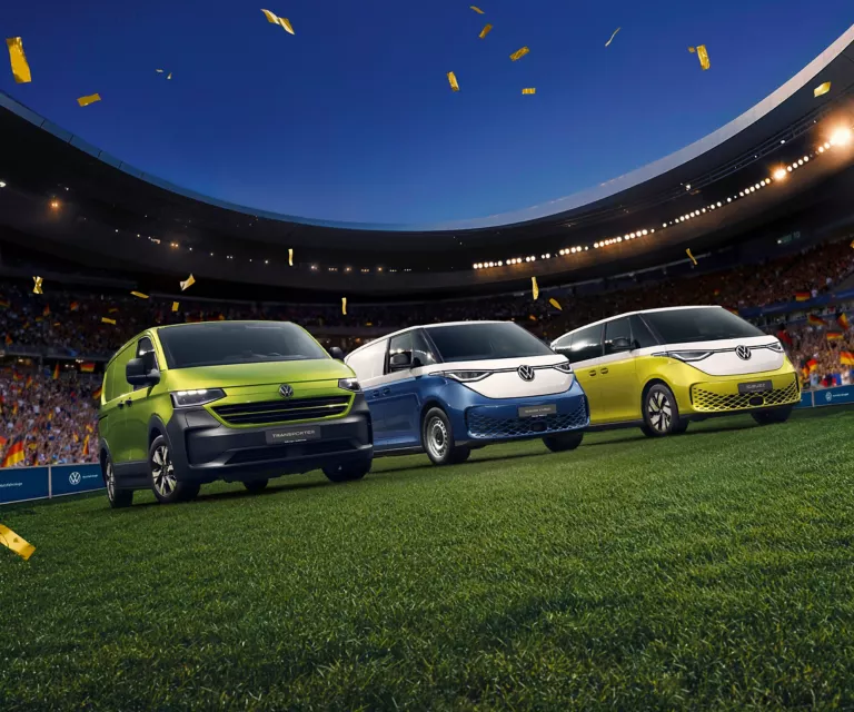 VW Transporter Kastenwagen, VW ID. Buzz Cargo und VW ID. Buzz stehen im Konfettiregen in einem Fußballstadion.