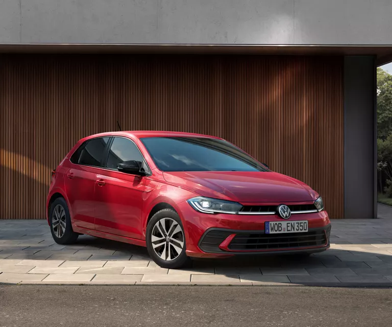 Ein VW Polo steht vor einem Haus mit Holzfassade.