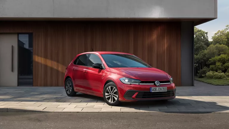  Ein VW Polo steht vor einem Haus mit Holzfassade.