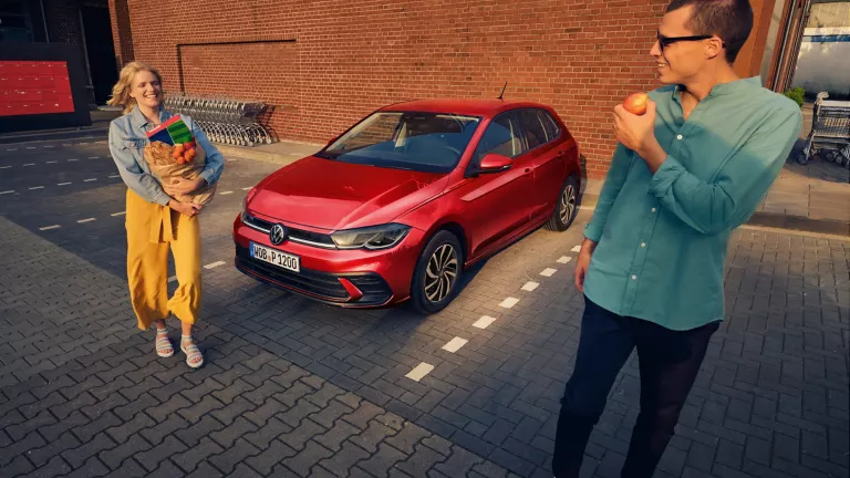 Zwei VW-Modelle vor einem Park geparkt mit Kirschblütenbäumen