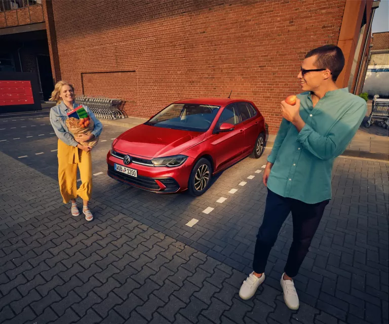 Zwei VW-Modelle vor einem Park geparkt mit Kirschblütenbäumen
