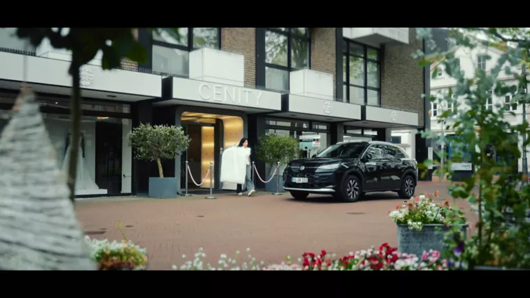 Gelber VW T-Roc SUV, Frontansicht, geparkt auf Asphalt, umgeben von Bäumen und Sträuchern.