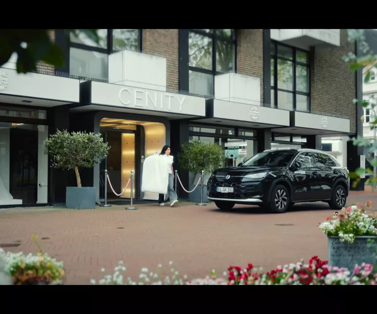 Gelber VW T-Roc SUV, Frontansicht, geparkt auf Asphalt, umgeben von Bäumen und Sträuchern.