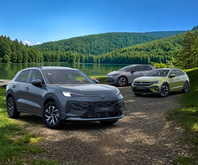 VW T-Roc, VW Taigo und VW ID.3 Neo parken an einem See.