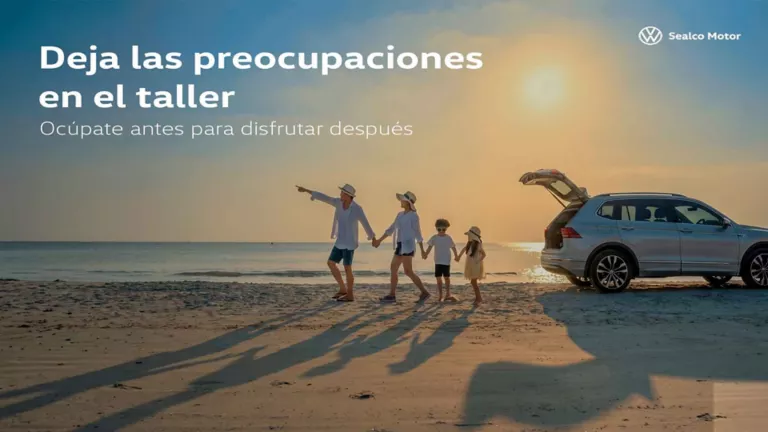 Una familia cogida de la mano en la playa señalando al horizonte junto a un Volkswagen blanco al atardecer