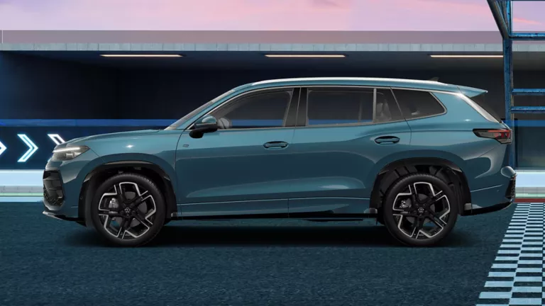 Seitenansicht eines blauen Tayron Sportwagens mit fünf Türen und sportlichen Felgen, auf einer Rennstrecke mit blauen und grauen Markierungen.