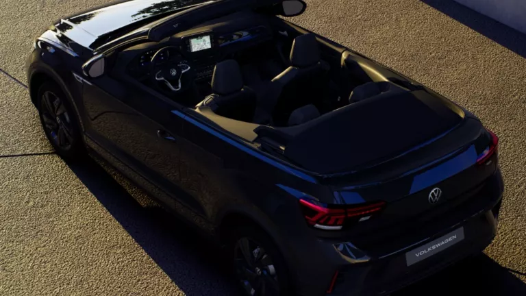 Ein schwarzes T-Roc Cabrio steht im Sonnenuntergang in einer Einfahrt.