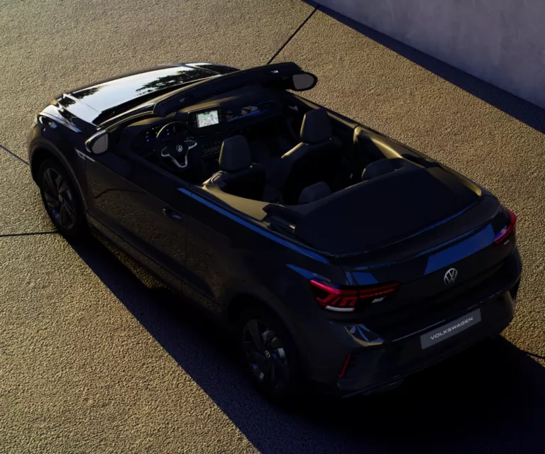 Ein schwarzes T-Roc Cabrio steht im Sonnenuntergang in einer Einfahrt.