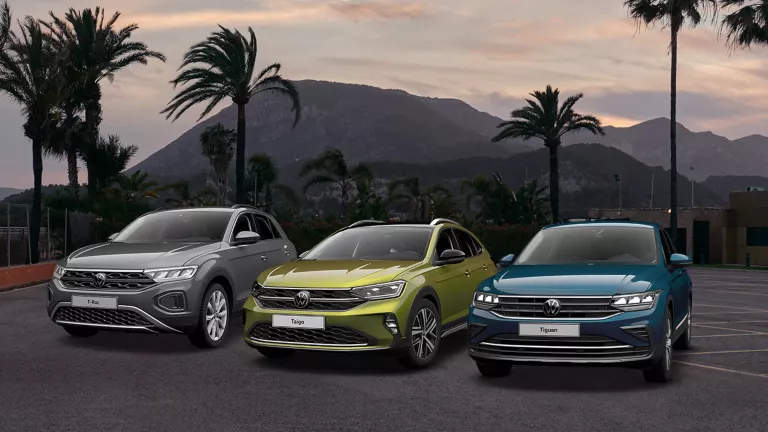 Der T-Roc, Taigo und Tiguan stehen auf einem Platz mit einem Berg im Hintergund.