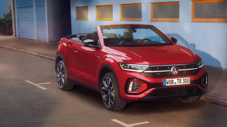 Ansicht der Front eines roten T-Roc Cabriolet mit geöffnetem Dach, parkend am Straßenrand. 