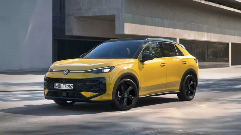 Eine gelber Volkswagen  T-Roc R-Line steht in 3/4-Frontansicht vor einem Gebäude.