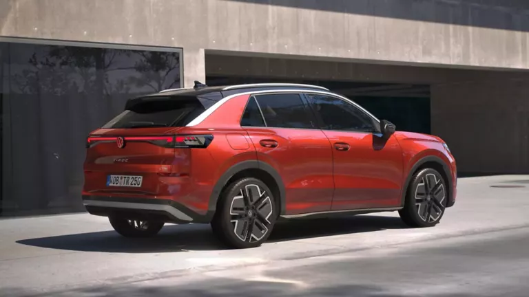Eine 3/4-Rückansicht eines roten Volkswagen T-Roc Style, parkend vor einem Gebäude.
