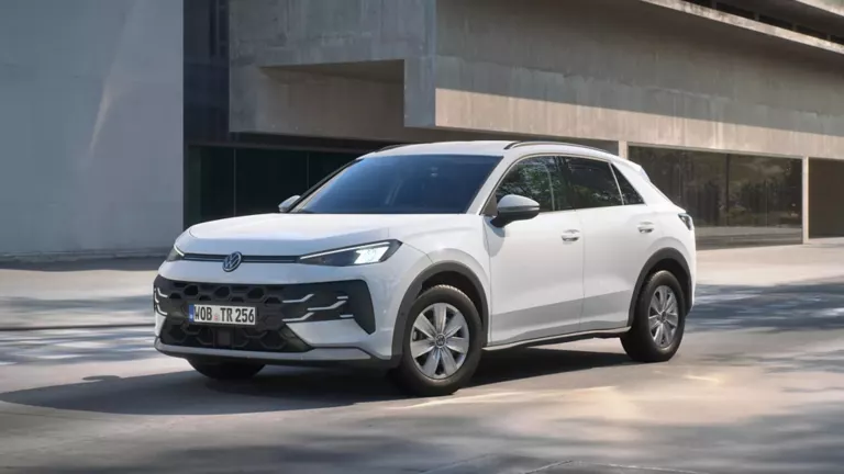 Ein weißer Volkswagen T-Roc Trend steht in 3/4-Frontansicht vor einem Gebäude.