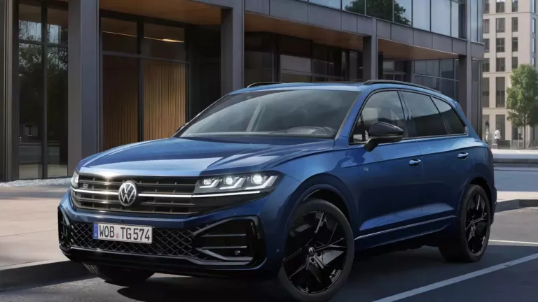 Ein dunkelblauer Touareg „FINAL EDITION“ parkt an einem Seitenstreifen vor einem futuristischen Gebäude. Im Hintergrund sind weitere Gebäude sowie grüne Bäume zu erkennen.