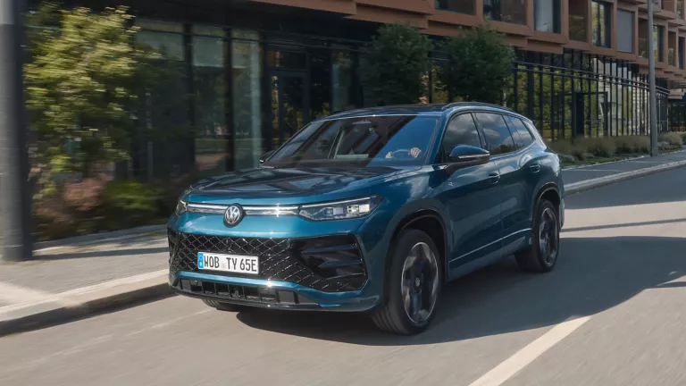 Gelber Volkswagen T-Roc und grauer Tiguan vor Kirschblüten auf einem Parkplatz.