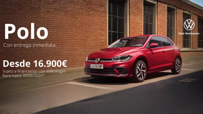 Un Volkswagen Polo rojo parado junto una pared de ladrillo