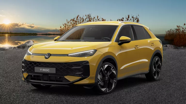 Frontale Ansicht eines gelben VW T-Roc, der auf Asphalt steht, vor Schilf und einem See.