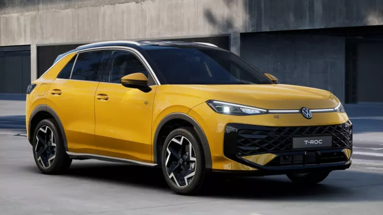 Eine gelber Volkswagen  T-Roc R-Line steht in 3/4-Frontansicht vor einem Gebäude.