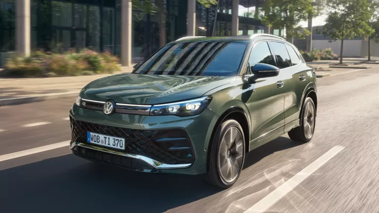 VW Tiguan, dunkelgrün, auf der Straße fahrend.