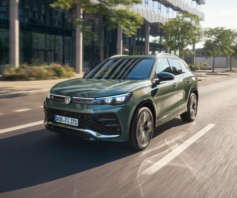 VW Tiguan, dunkelgrün, auf der Straße fahrend.