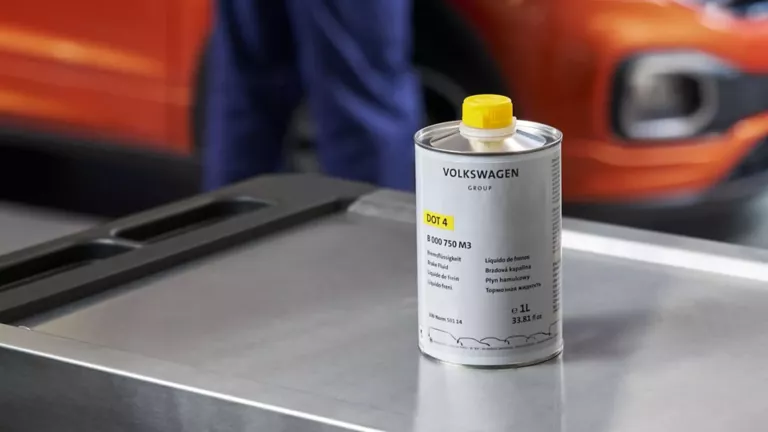 Dose Volkswagen Original Bremsflüssigkeit auf einem Rollcontainer, im Hintergrund ein VW T-Cross