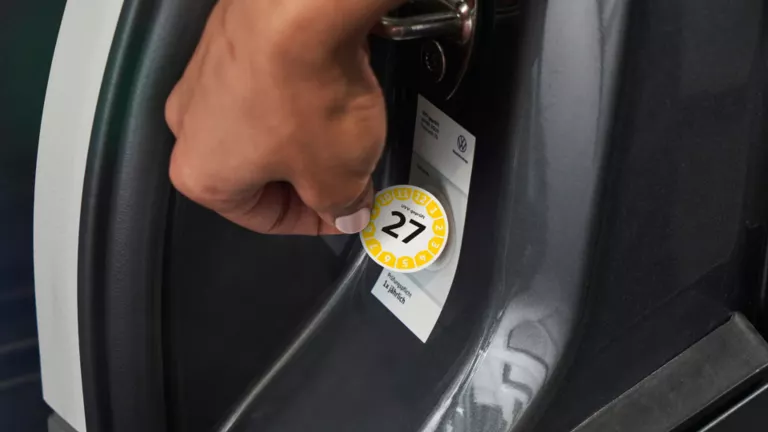 Ein UVV-Prüfsiegel wird an einem VW Fahrzeug angebracht.
