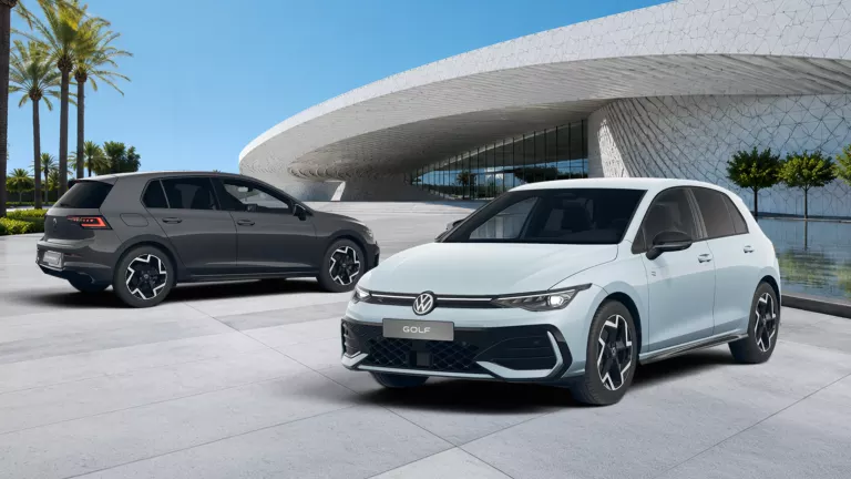 Zwei VW Golf R-Line, einer in Weiß und einer in Dunkelgrau, vor modernem, rundem Gebäude mit Glasfassade und Palmen im Hintergrund.